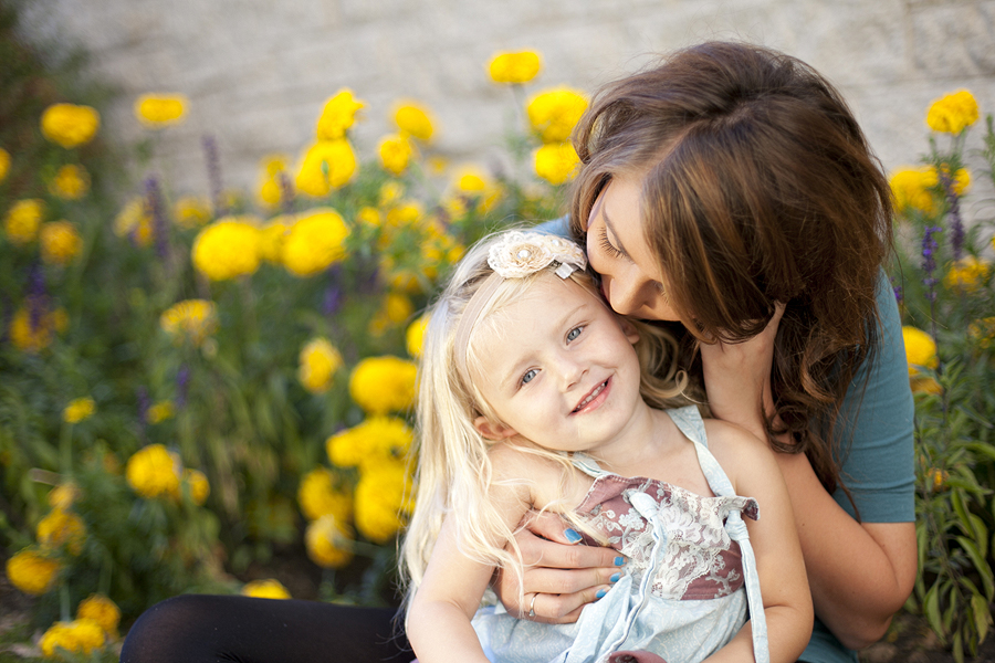 mom kissing a girl with yellow flowers around by helga himer photography of sudbury
