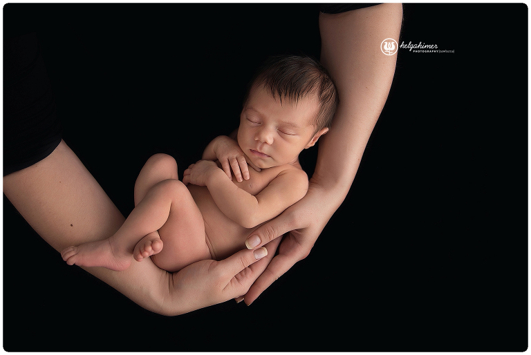 black fabric shot of a newborn little baby in her mothers arms sleeping infant by helga himer photography of sudbury