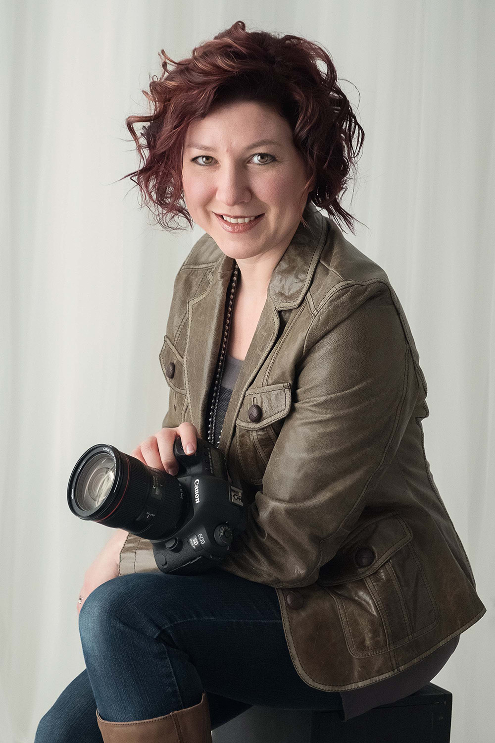 Studio portrait of Helga Himer of Helga Himer Photography, holding her choice Canon camera.